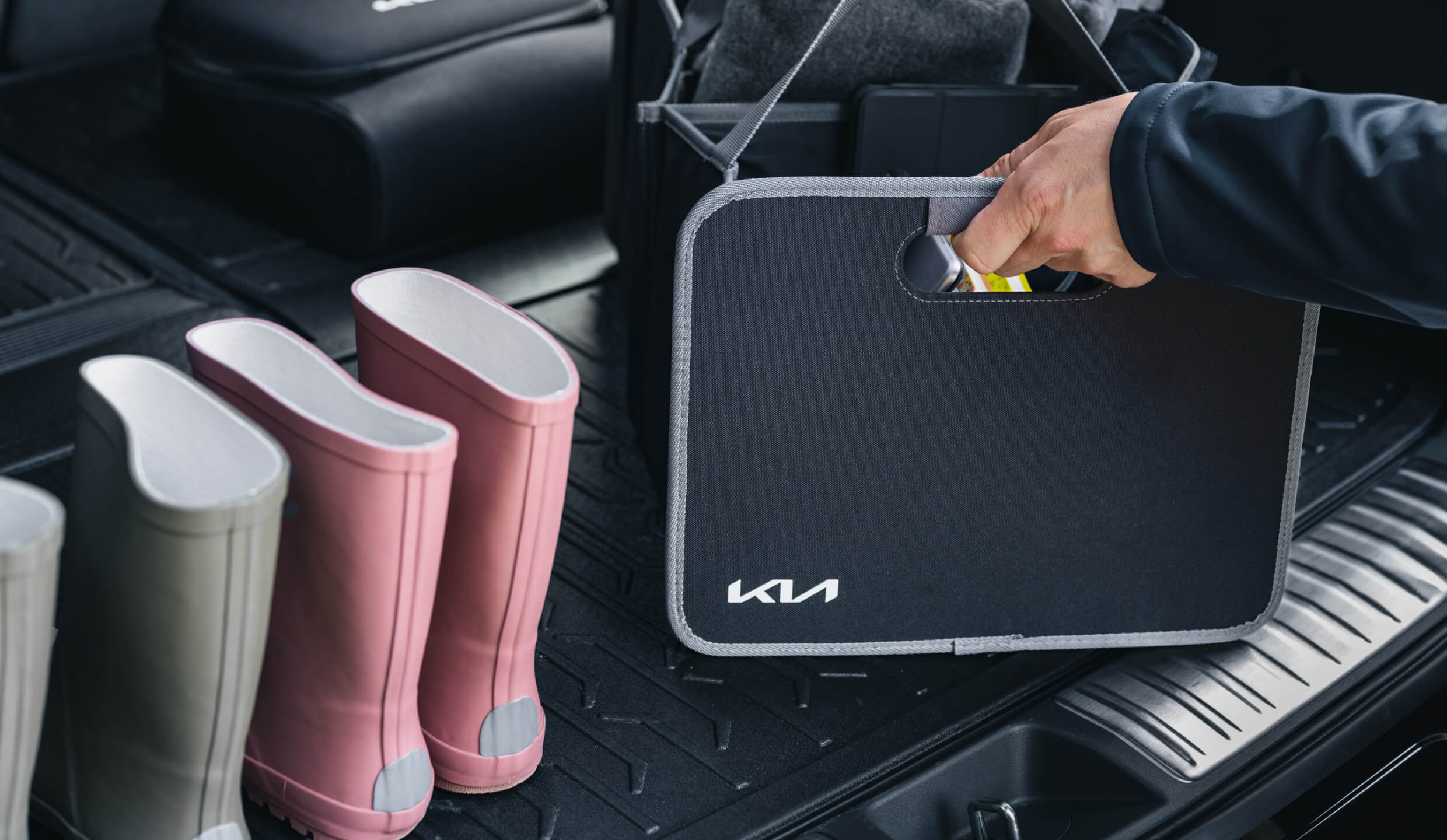 Man places Kia Trunk Organiser from the Kia Collection onto a Kia Trunk Mat to keep the boot clean and tidy.