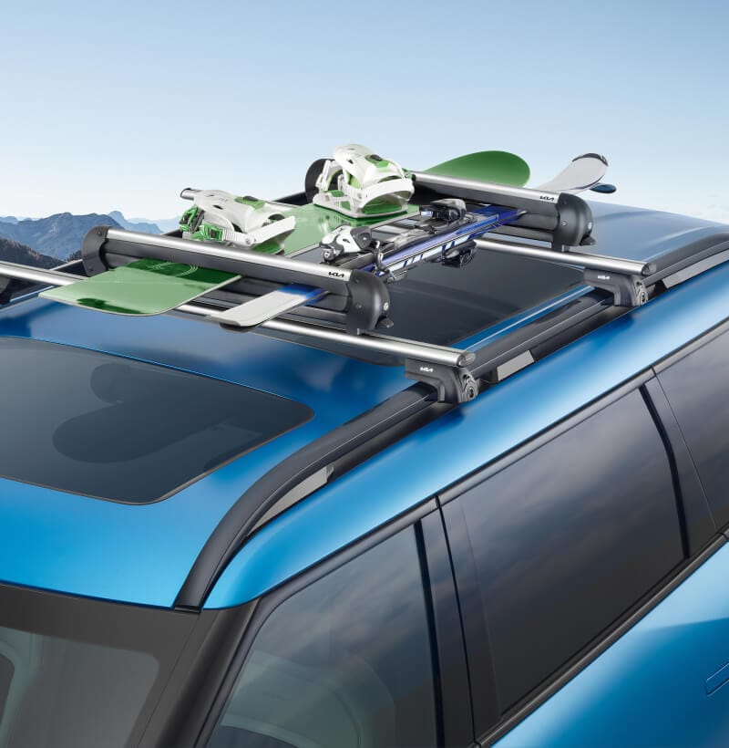 The Kia Ski and Snowboard Carrier mounted on a Kia EV9 safely transports a snowboard and a pair of skis.