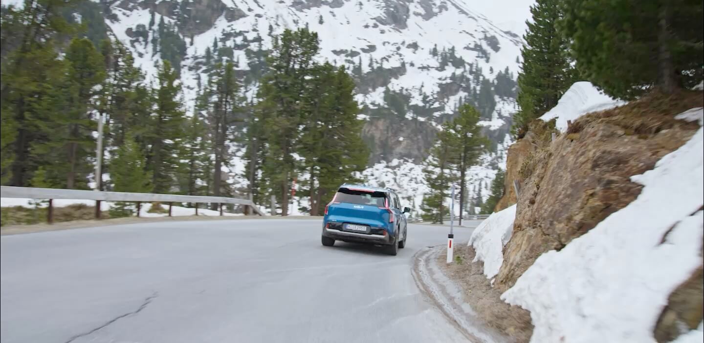 Kia technicians install Genuine Brake Pads and Discs, enabling the Kia EV9 to brake safely on steep curves of a scenic mountain road.