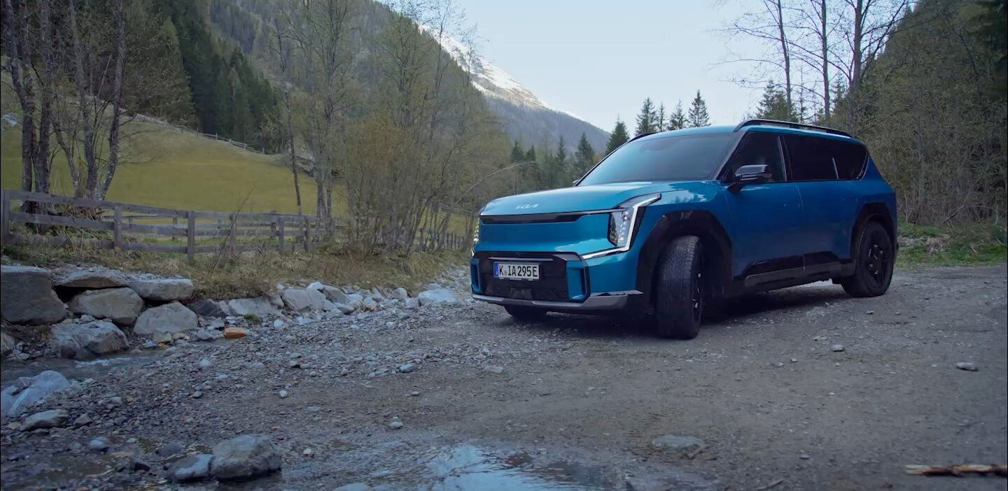 A Family enjoys a hike by a mountain river, supported by Kia Collection items that enhance their outdoor experience.