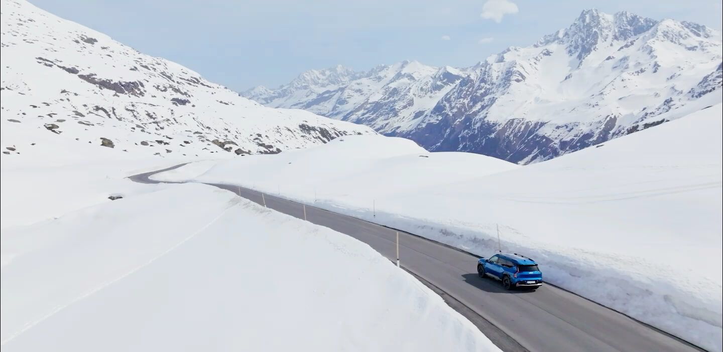 Kia receives a Vehicle Health Check and drives safely along a scenic route toward snow-covered mountains.