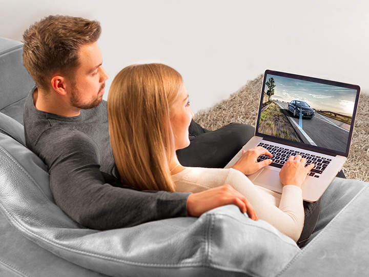 Una pareja está sentada en el sofá viendo un vídeo de Kia.