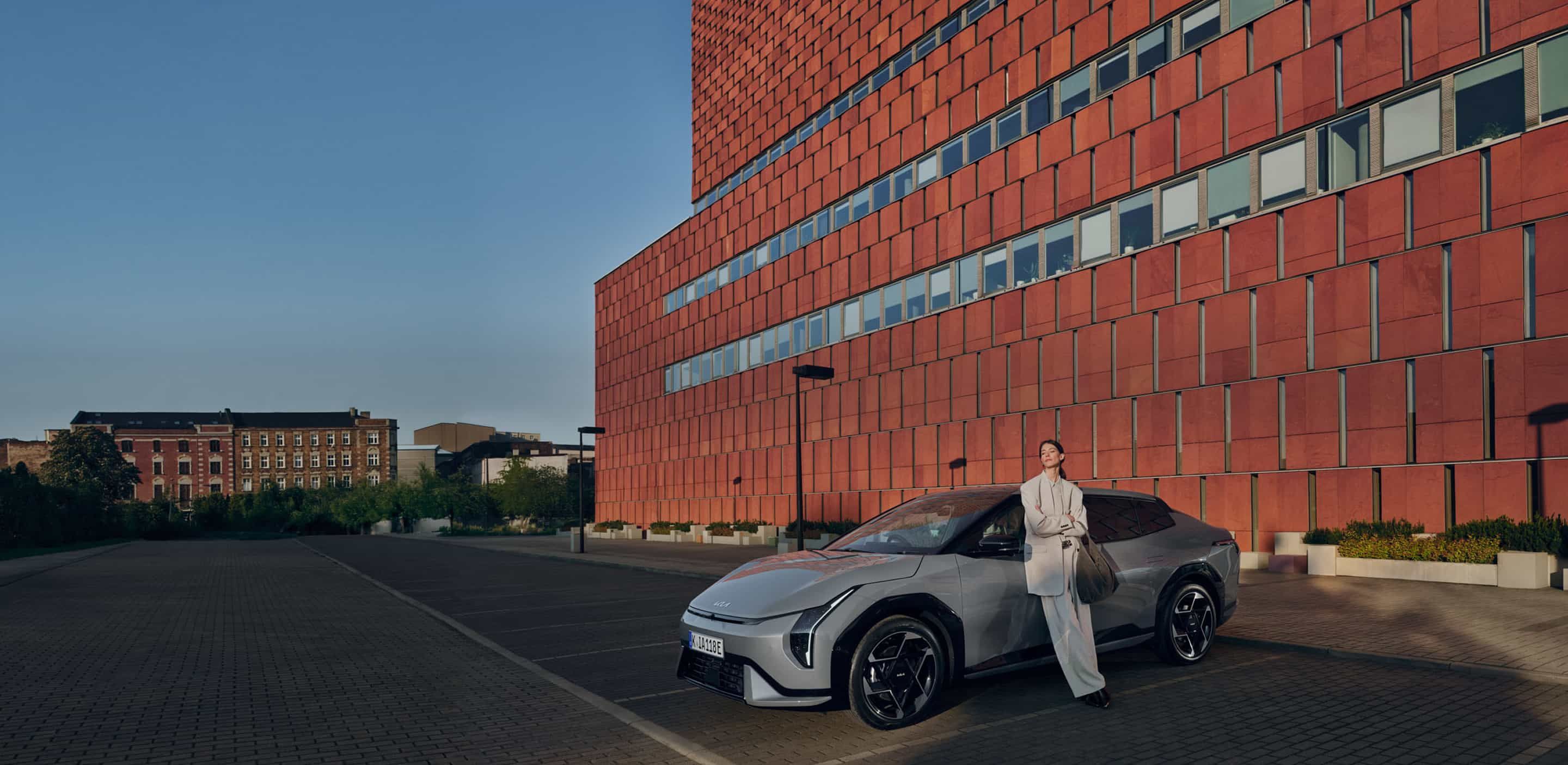 A woman enjoying the sunshine while standing next to her Kia EV6.