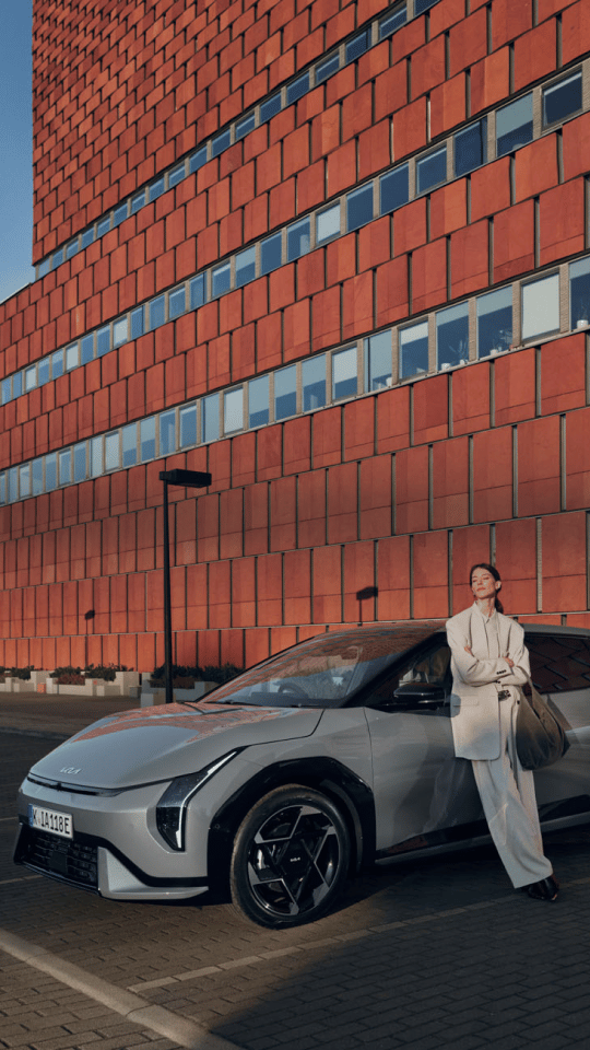 A woman enjoying the sunshine while standing next to her Kia EV6.