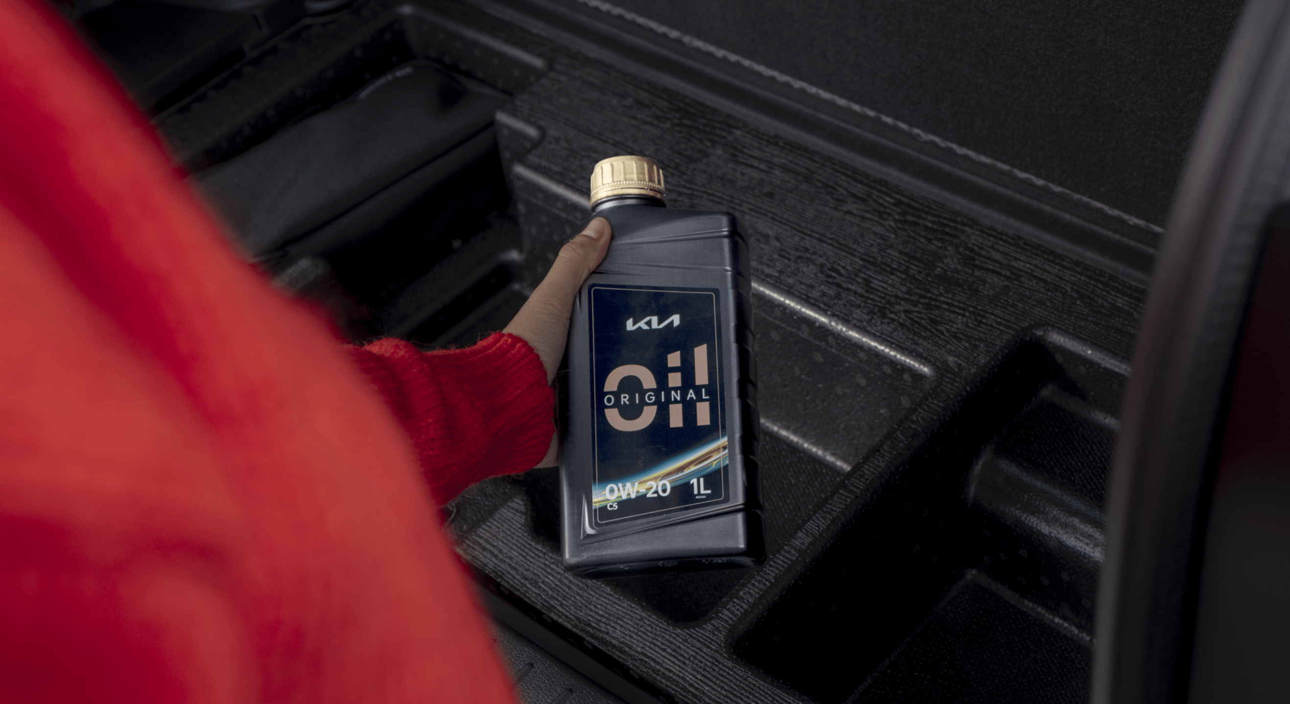 Kia customer is holding a bottle of Kia Original Oil in his hand.