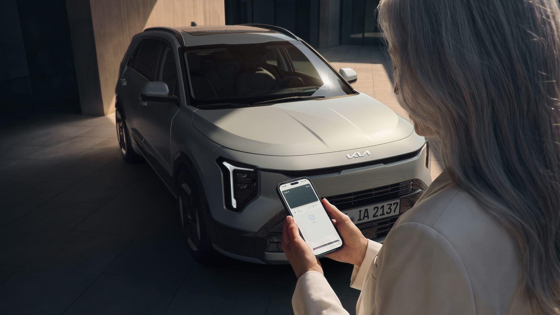 Mujer con un móvil delante de un Kia Niro