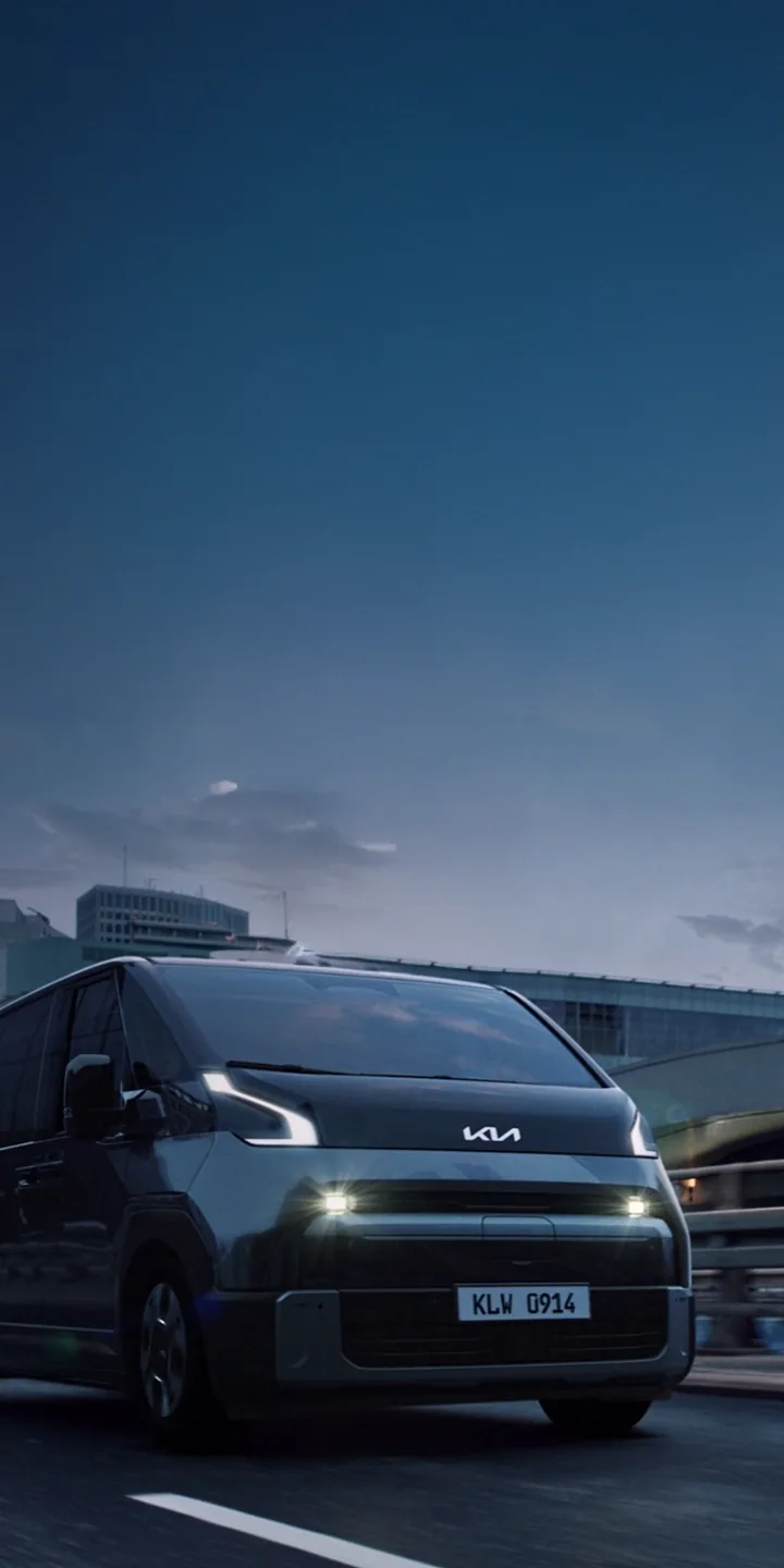 The Kia PV7 on a city road with high-rise buildings in the background.