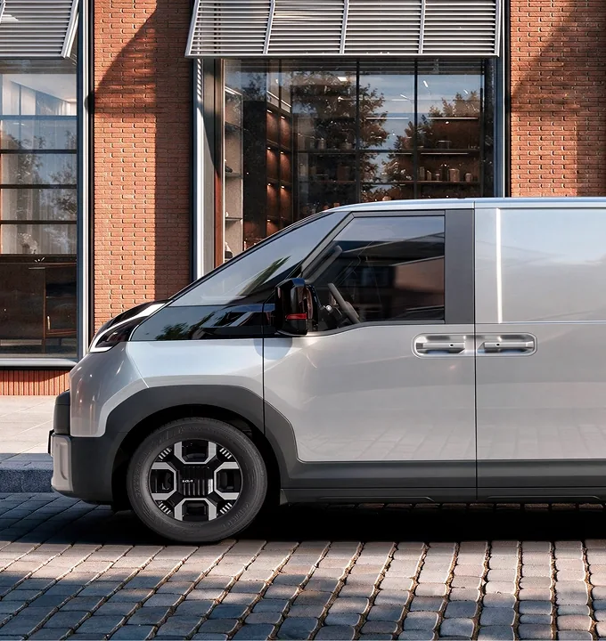 Side view of the Kia PV7 parked outside a brick building.