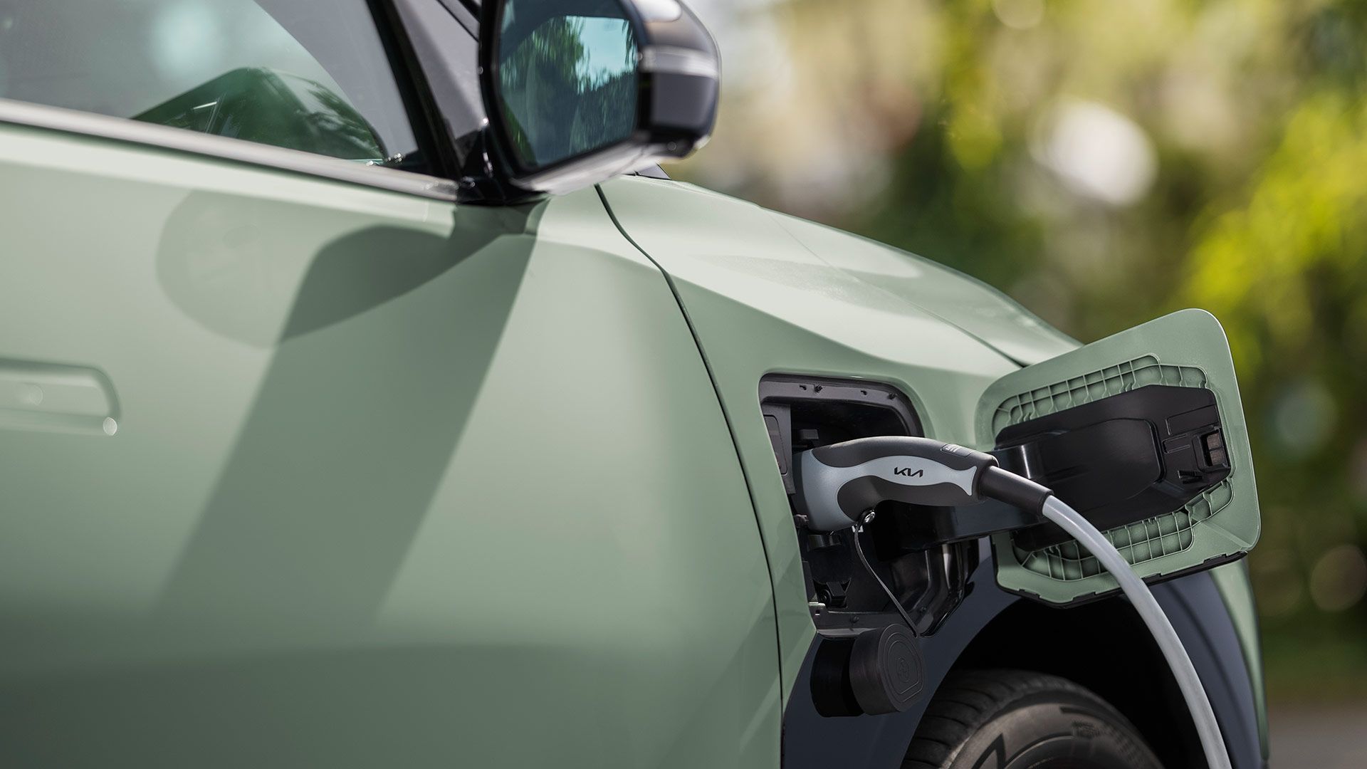 Close up of a green Kia EV3 with charging cable plugged into the charging port