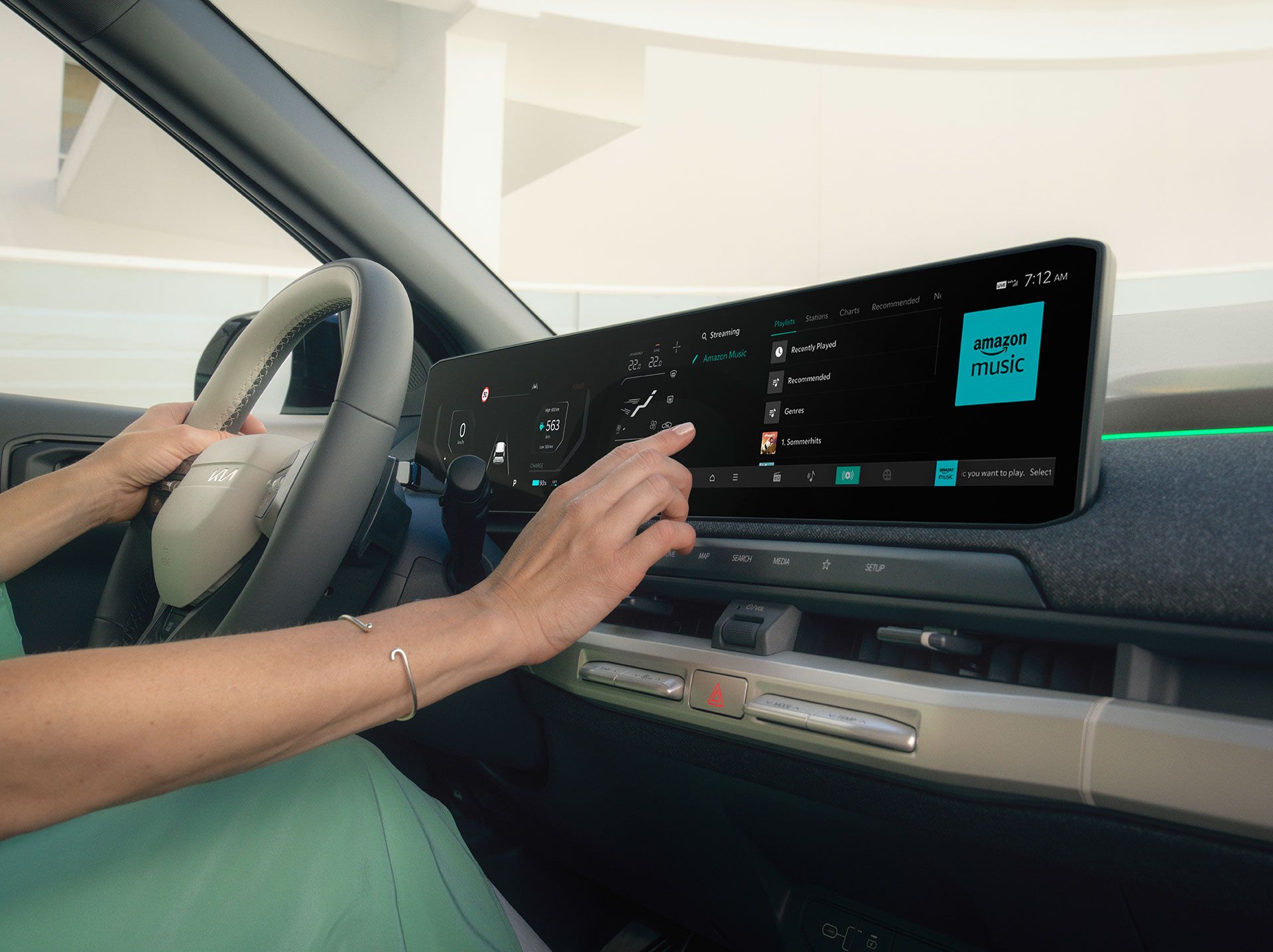 Person using touch screen in Kia EV3 while holding the steering wheel, with dashboard and controls visible.