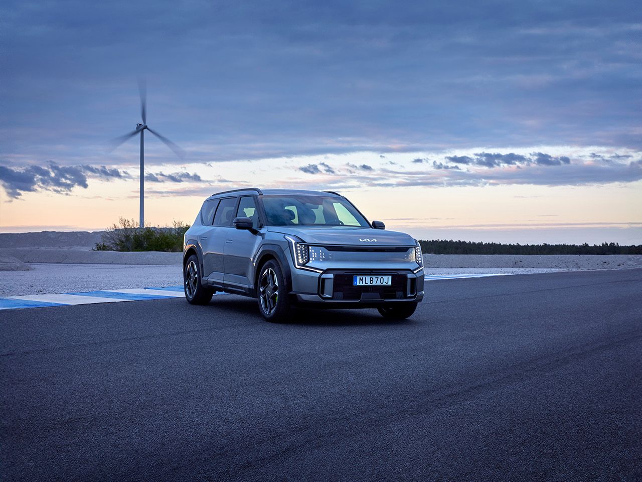 Kia EV9 GT på racingbana med vindmölla i bakgrunden.
