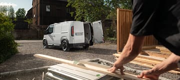 Kia PV5 Cargo med en snickare i arbete i förgrunden.