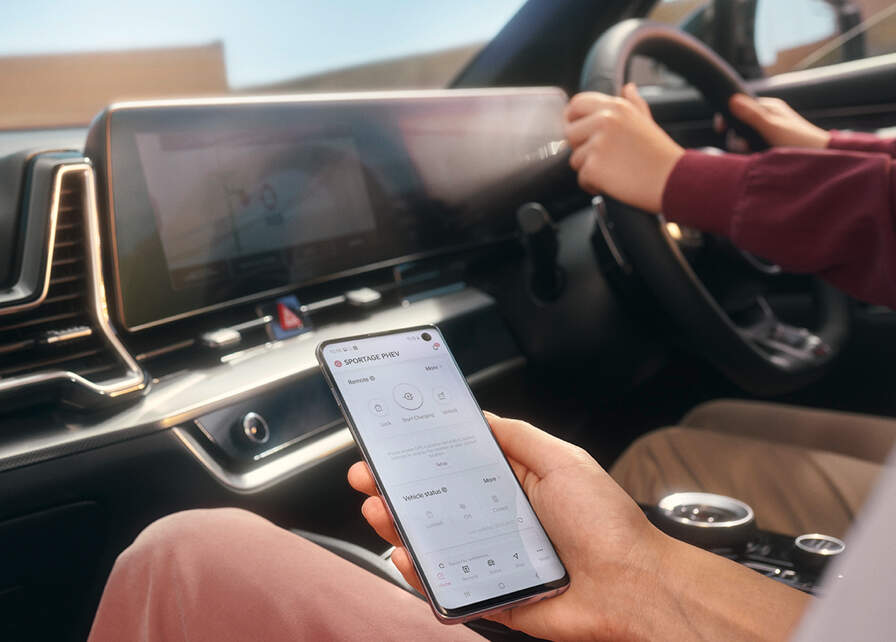 Man holding a smartphone with the Kia Connect App on the screen.