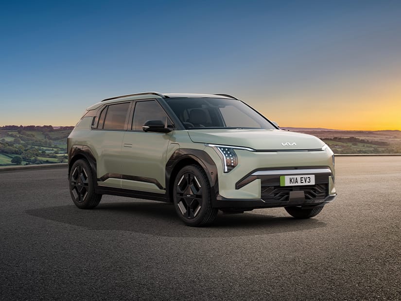 Kia EV4 in Blue Flame parked on an open road with a scenic countryside backdrop at sunset