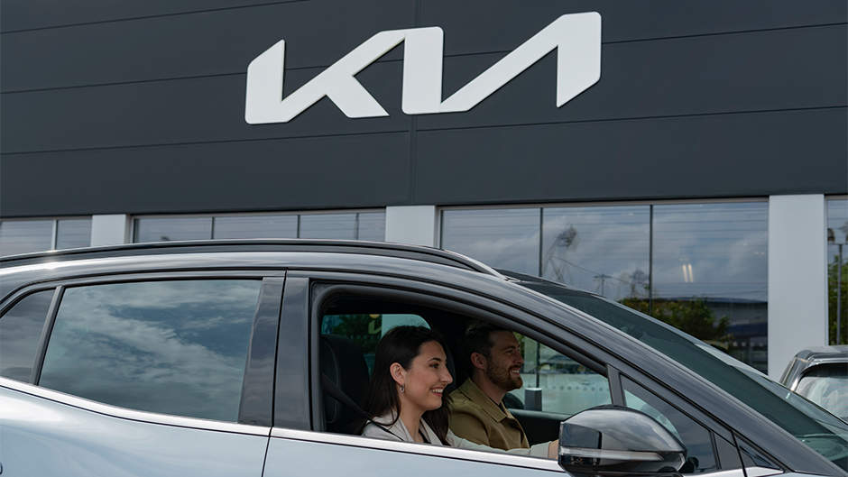 Kia dealership with models driving a Sportage