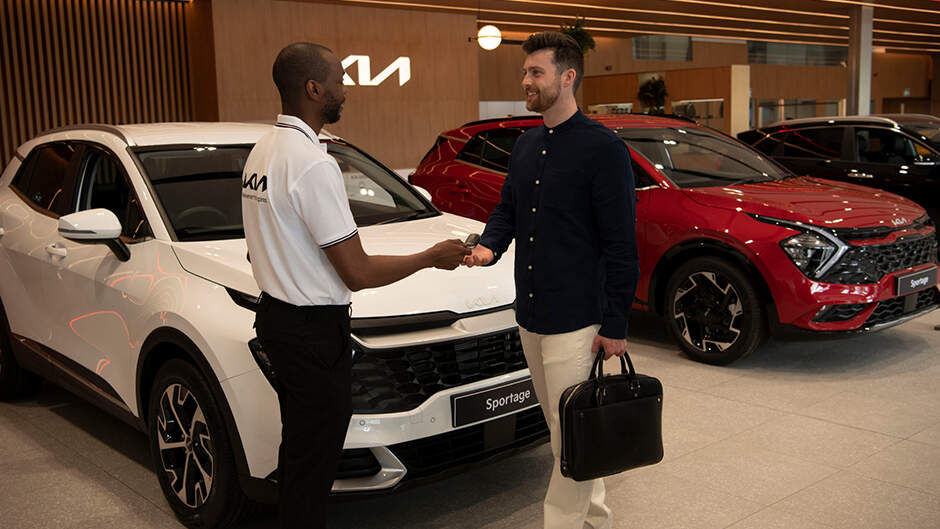 Kia dealership, with models shaking hands