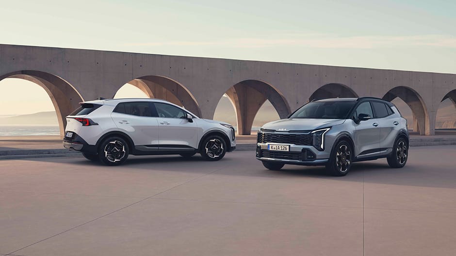 Two Kia Sportage's parked by a concrete structure