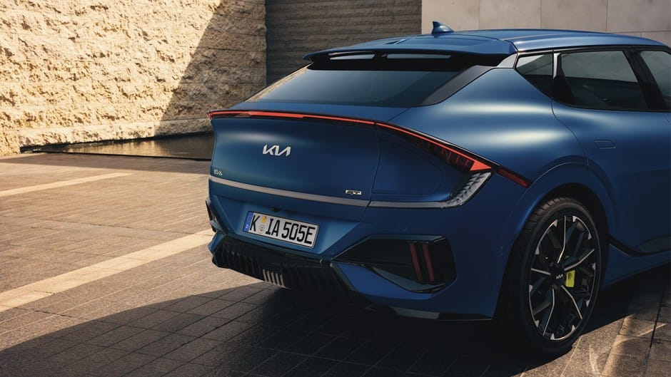 The Kia EV6 GT is parked by a brick building, with a small area of water.