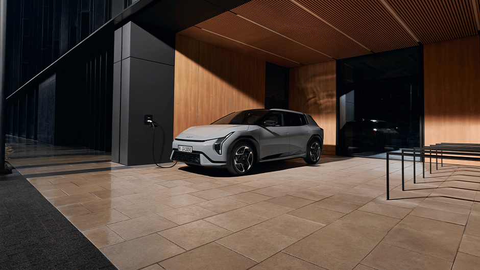 The Kia EV4 in Wolf Grey charging outside a house