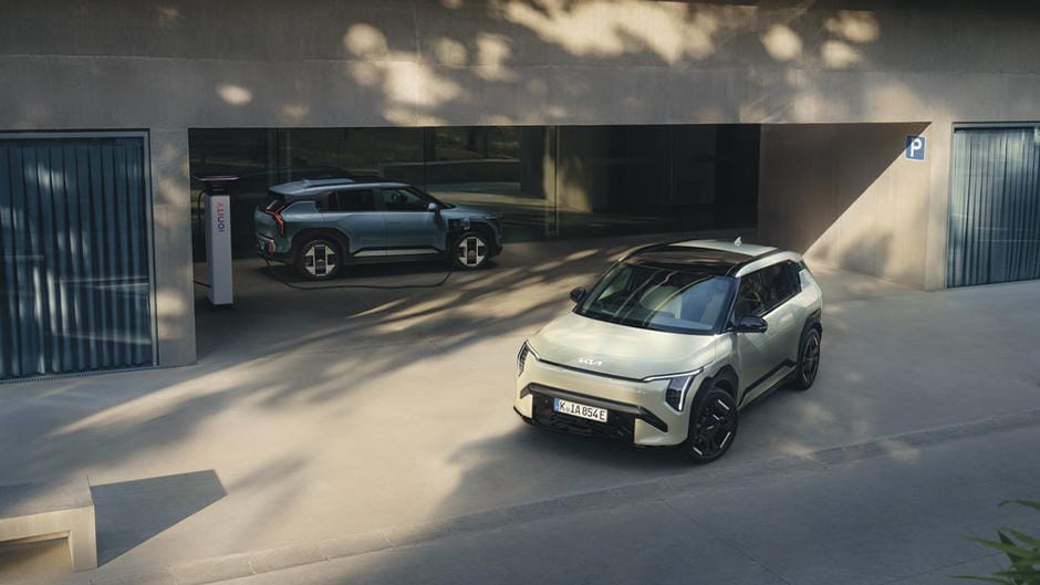 Two Kia EV3’s. EV3 Air in Frost Blue is charging, whilst the EV3 GT-Line S in Pistachio Green is parking.