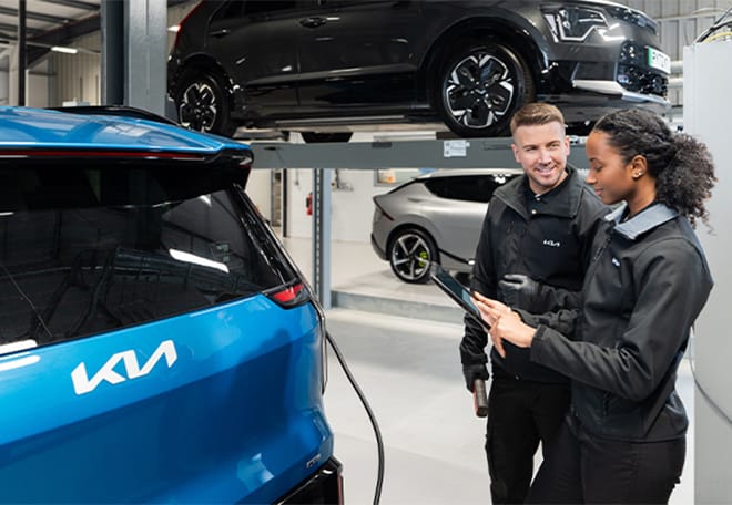 A Kia technician performing a diagnostic check using a diagnostic tool on a Kia EV9.
