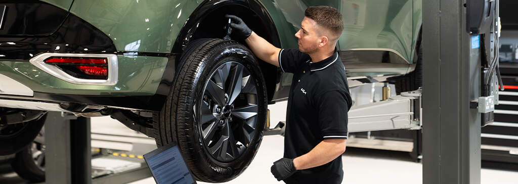  A mechanic checking a Kia car tire in a garage.