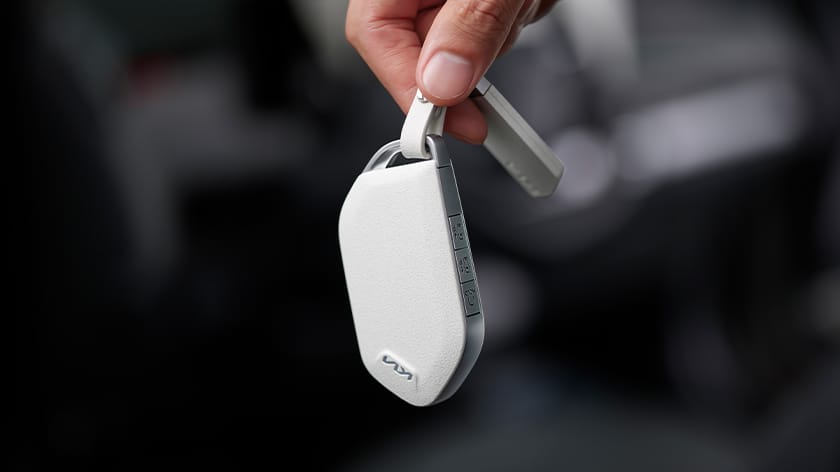 Close-up of a hand holding a white Kia smart key