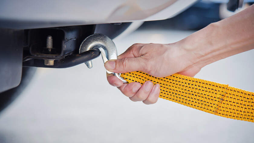 Close-up of a hand holding yellow car towing strap 