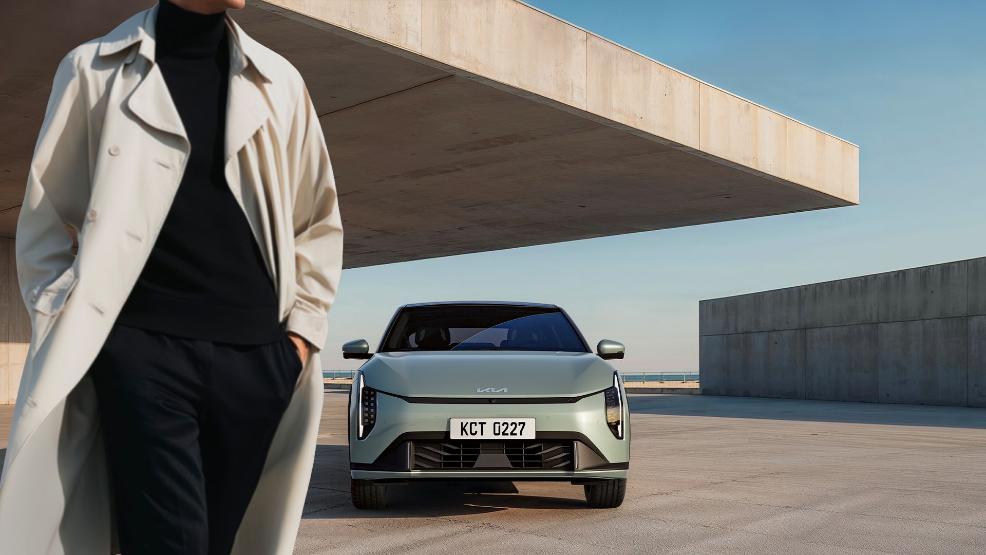 Person walking past a parked Kia EV4 outdoors