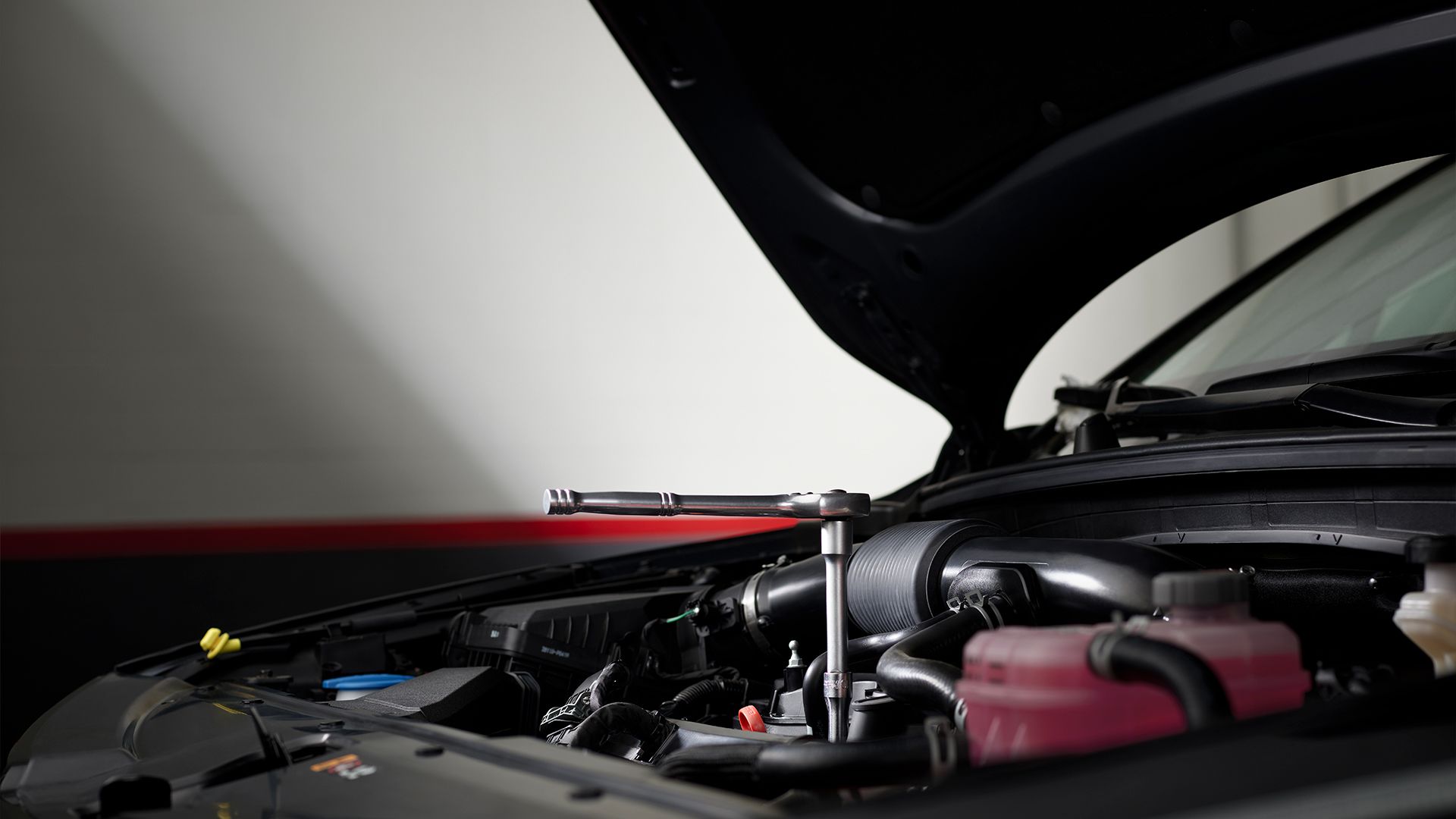 Open hood view of a Kia Sportage with a torque wrench on engine components