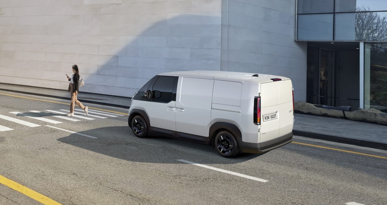 The Kia PV5 Cargo stopped at crosswalk while a pedestrian walks by