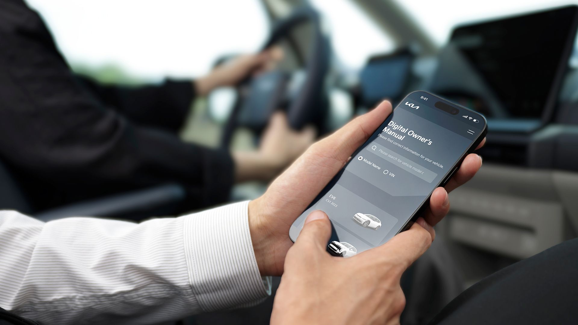 Kia PV5’in içinde, akıllı telefonundan kullanıcı kılavuzunu inceleyen yolcu