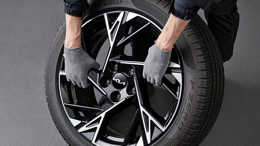 Bakım sırasında bir Kia K5 lastiğini kontrol eden teknisyen