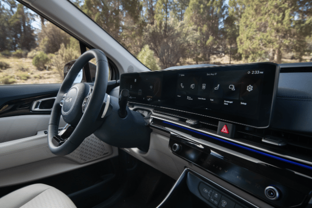 2025 Kia Carnival MPV Hybrid, three-quarter view of the Dual Panoramic Display with command options like phone, voice memo, and passenger view on the screen 