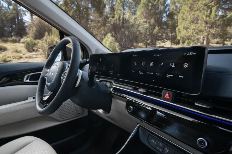 2025 Kia Carnival MPV Hybrid, three-quarter view of the Dual Panoramic Display with command options like phone, voice memo, and passenger view on the screen 