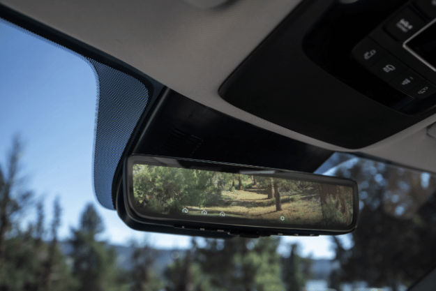 Kia vehicle interior, zoomed in view of the digital display rearview mirror showing trees and bushes in the screen