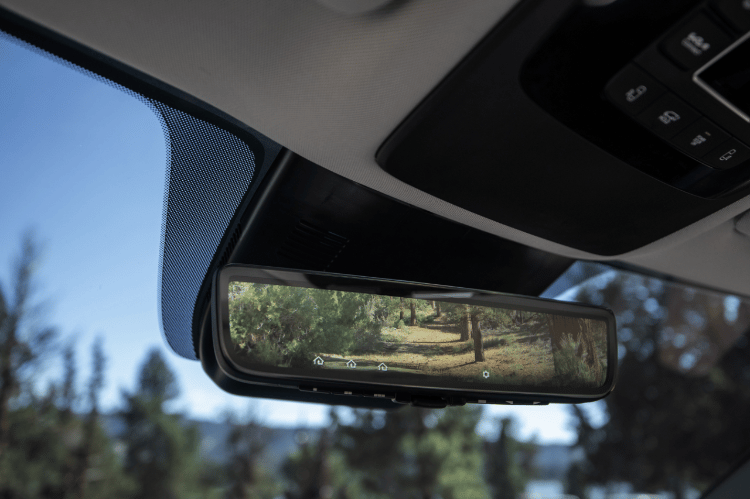 Kia vehicle interior, zoomed in view of the digital display rearview mirror showing trees and bushes in the screen