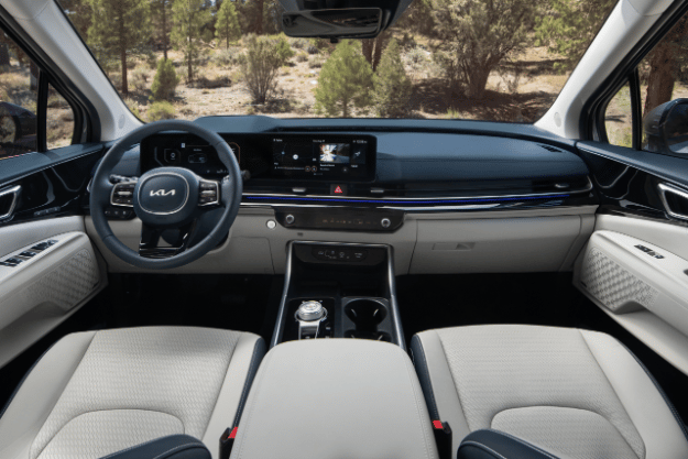 2025 Kia Carnival MPV Hybrid interior, full view of the front seat sections and dashboard, including the Dual Panoramic screen and driver's console