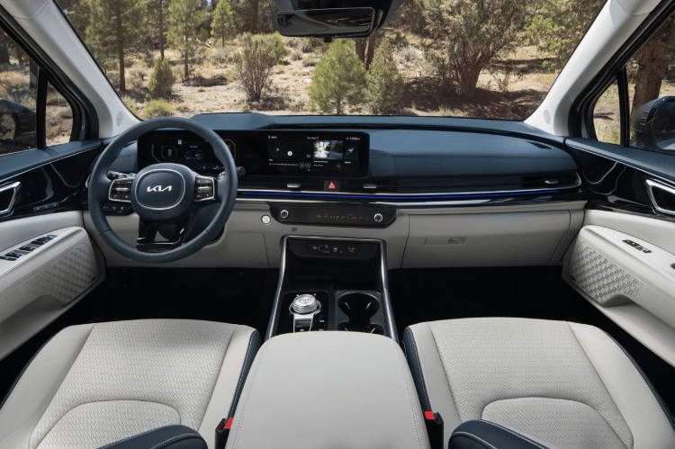 2025 Kia Carnival MPV Hybrid interior, full view of the front seat sections and dashboard, including the Dual Panoramic screen and driver's console
