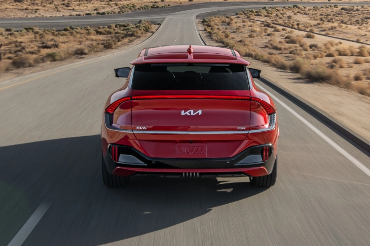 2024 Kia EV6 In Red Driving On A Desert Highway Rear-View 