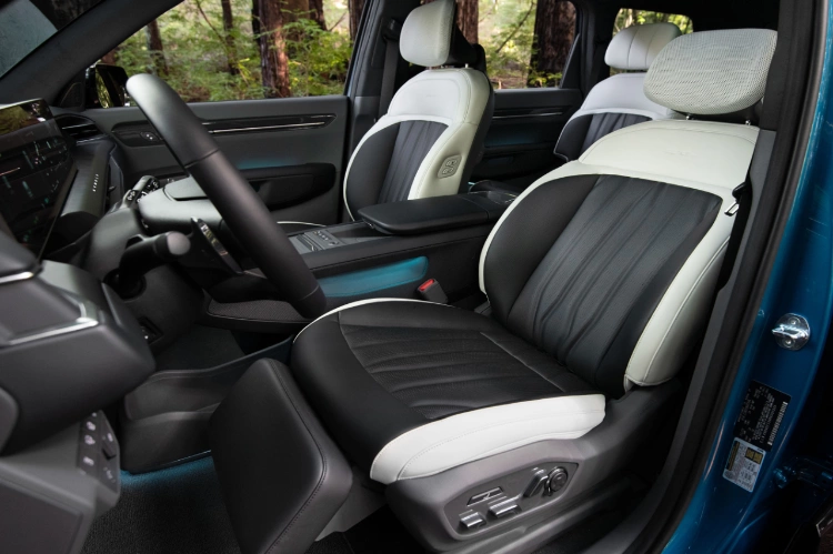 2024 Kia EV9 back view with the trunk open and third row seats folded down, packed with an extra large cooler, duffle back, backpack, blanket, and foldable chair