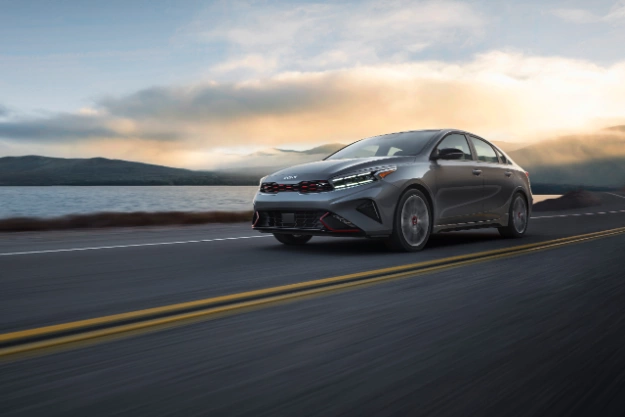 2022 Kia Forte in gray, action shot on coastal highway with view of front and driver side