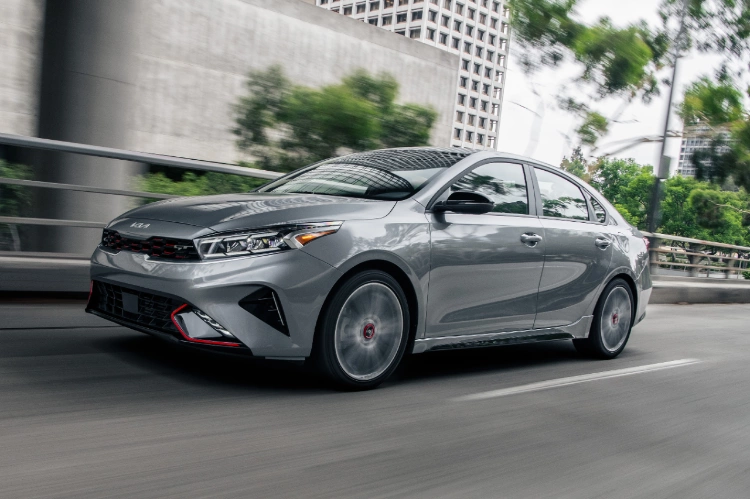 2022 Kia Forte in gray, mid-acceleration action shot with view of front and driver side