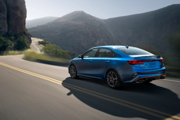 2022 Kia Forte in gray, action shot on a mountain highway with view of rear and driver side