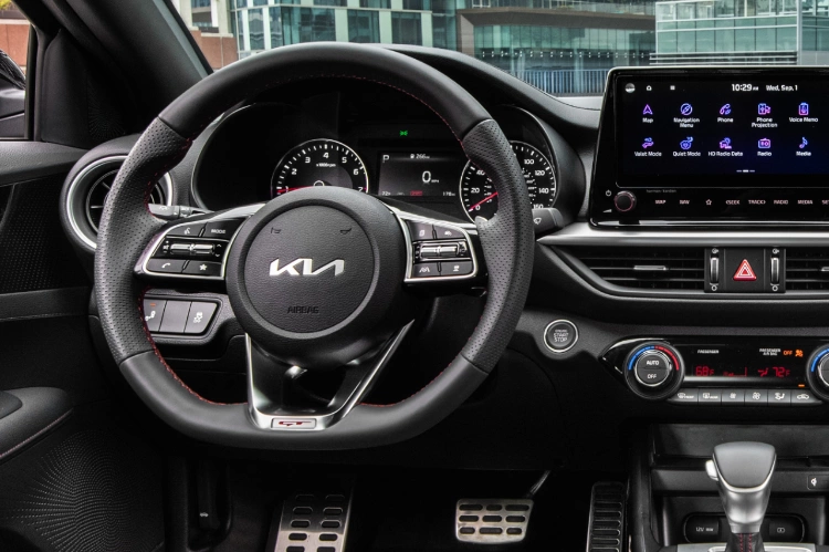 2022 Kia Forte, close-up shot of steering wheel, center console features, infotainment screen applications, and push to start ignition