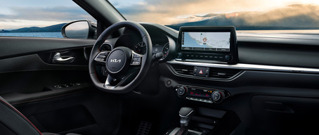 2022 Kia Forte with black interior, full cockpit view highlighting steering wheel controls, center console technology, and large touch screen monitor with navigation displayed