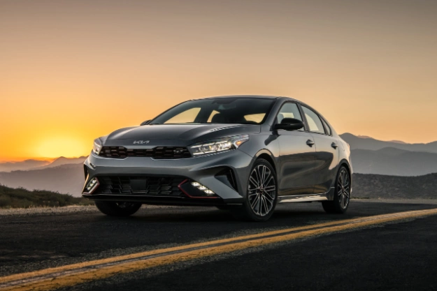 2023 Kia Forte Driving On An Open Road At Sunset Three-Quarter View