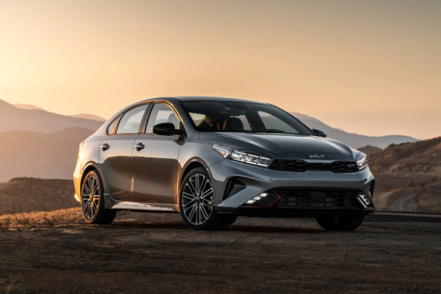 2024 Kia Forte in grey parked against a mountain sunset, three-quarters view