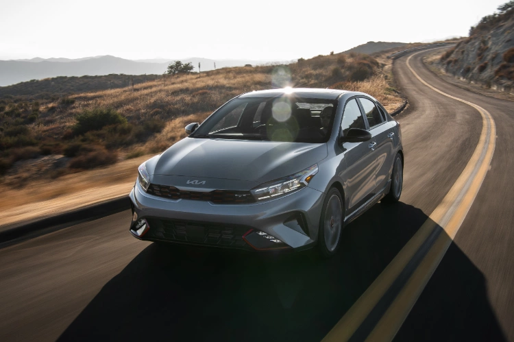 2024 Kia Forte driving over a twisting mountain road, high front view