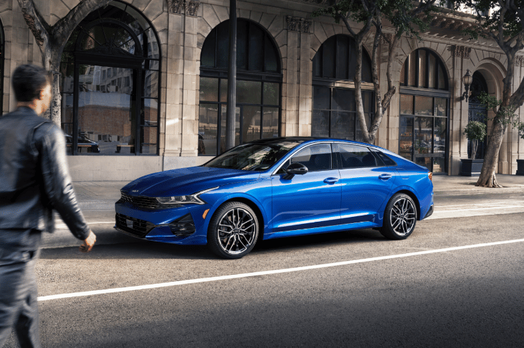 2022 Kia K5 Driving In A City Three-Quarter View